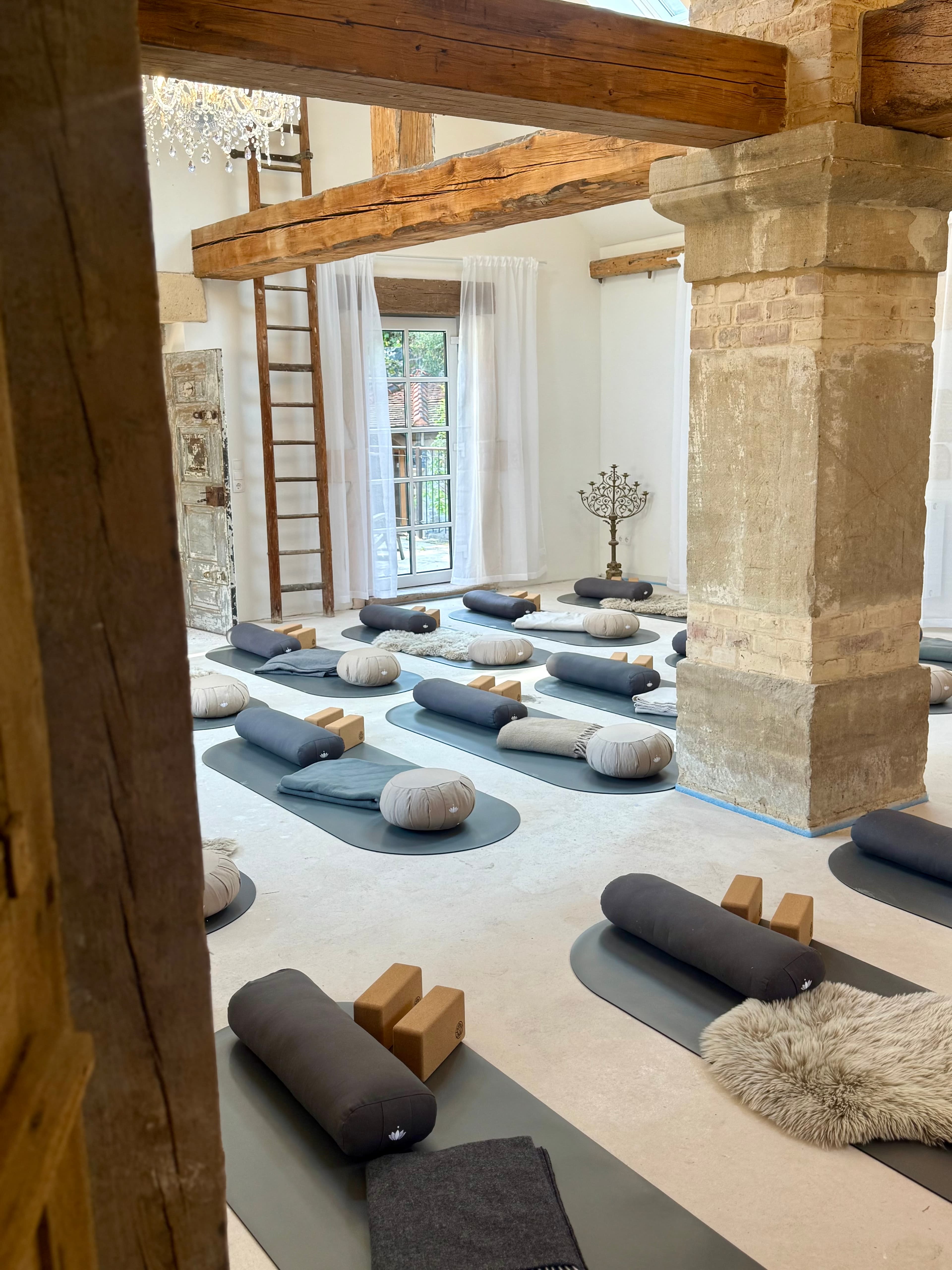 Yogaraum mit Matten, Bolstern und alten Steinsäulen