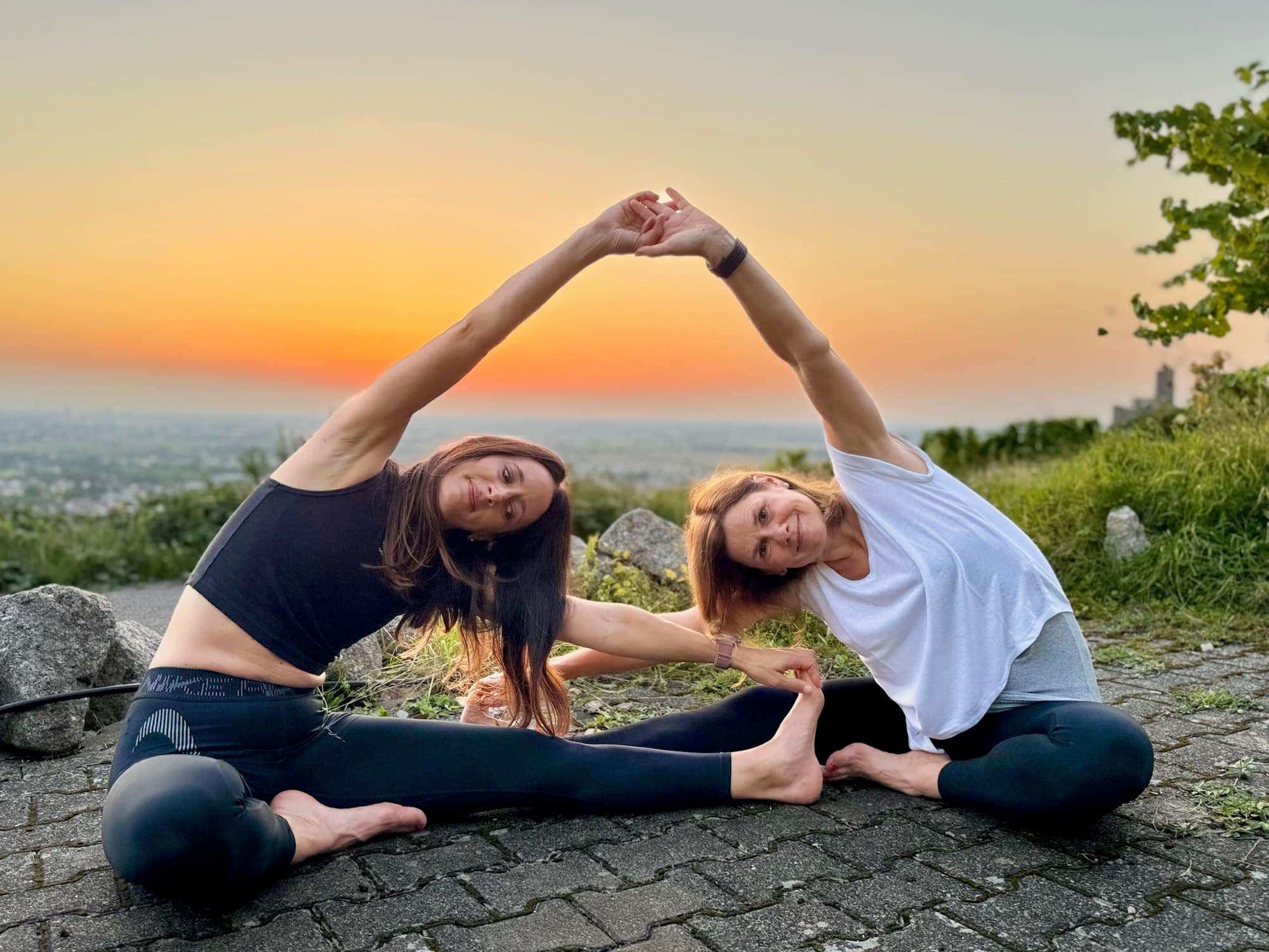 Tanja und Carolin in einer Yoga-Pose im Licht der Abendsonne